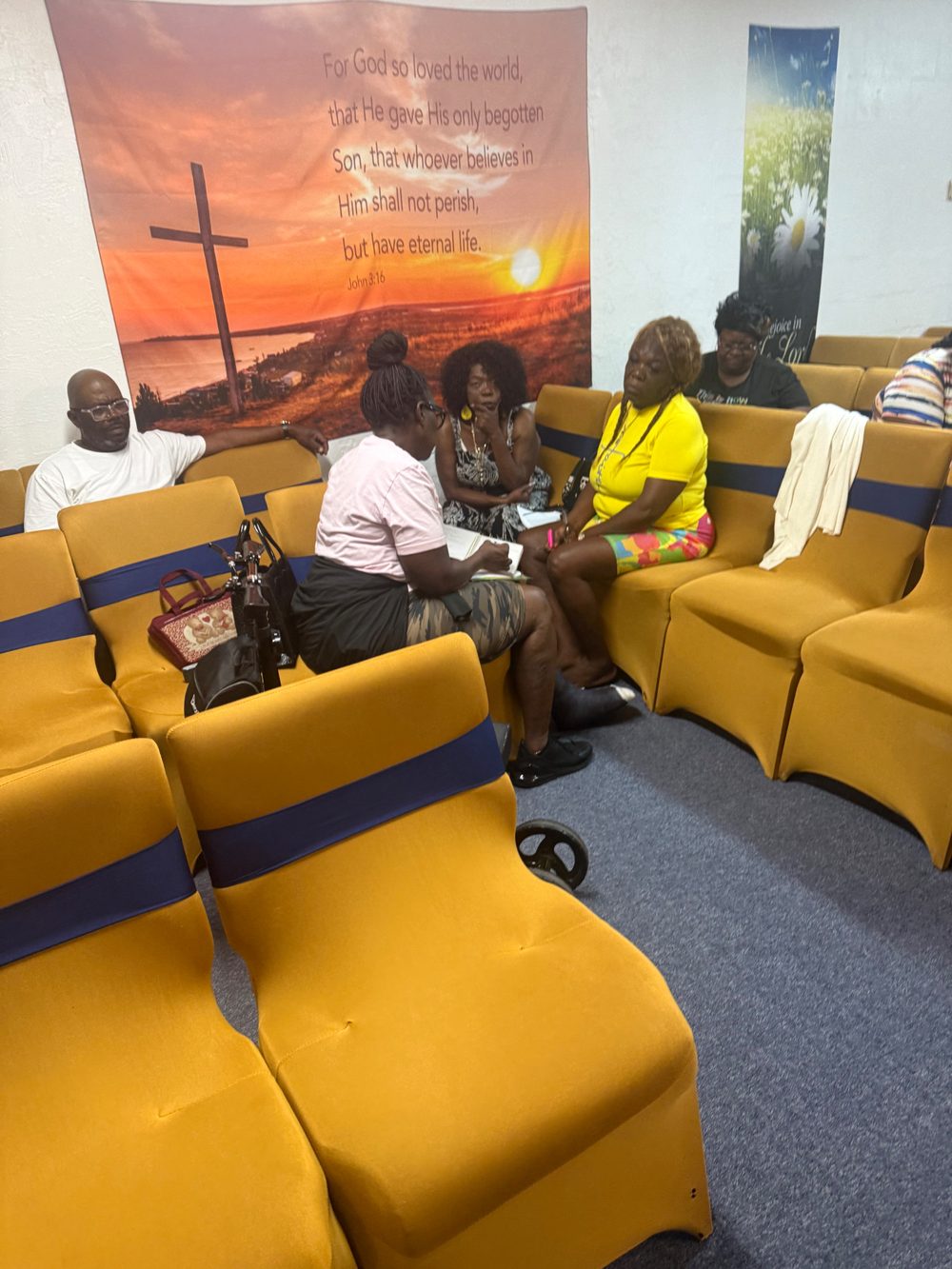 A small group gathered close together in the corner of the sanctuary, studying the Word and taking notes